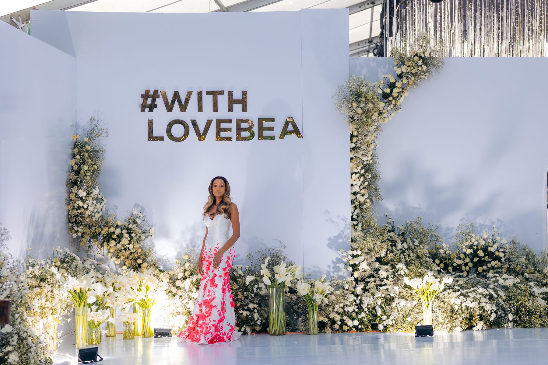 With Love, Bea — Beatrice at the signature floral wall, Kili Seasons, Arusha, by Kevins Events
